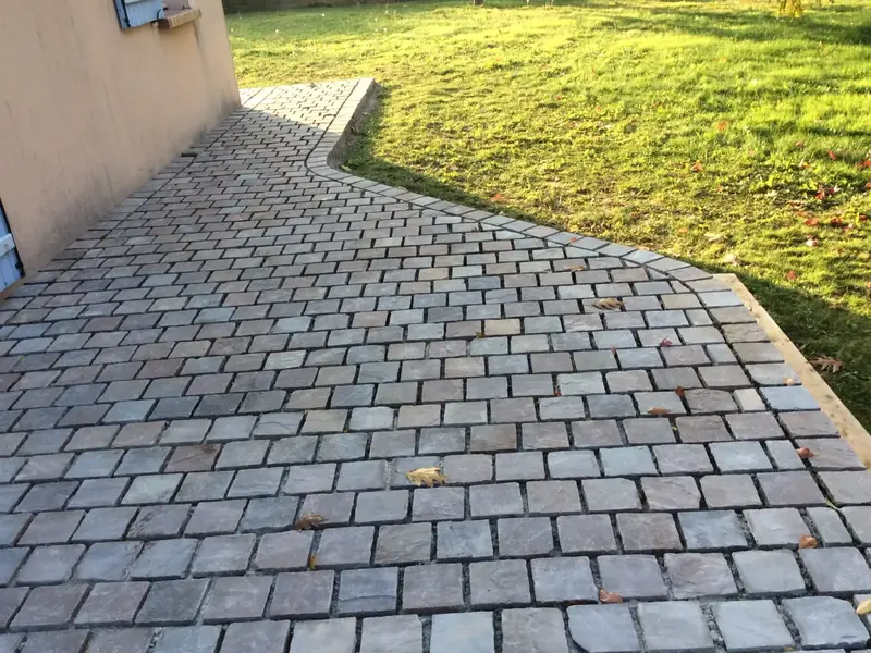 Allée pavée terminée entre la maison et la pelouse