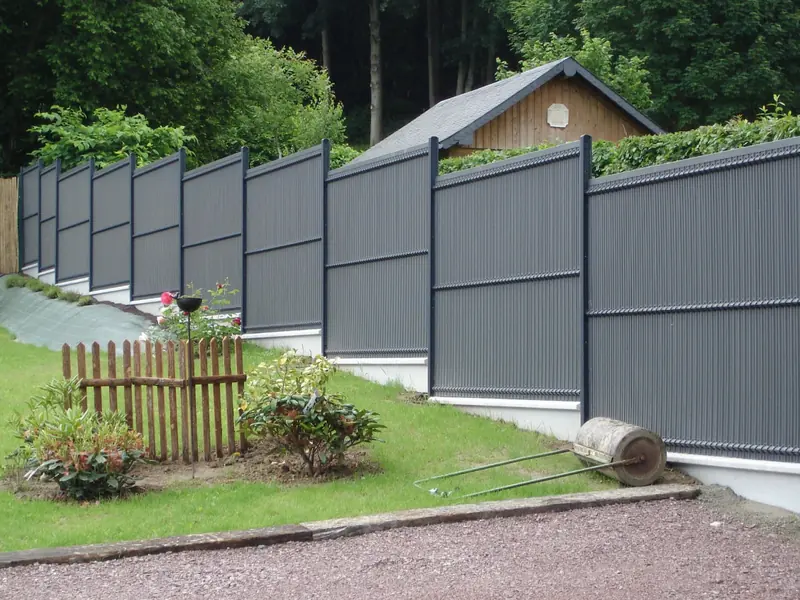 Clôture en panneaux rigides posée sur un muret devant une maison