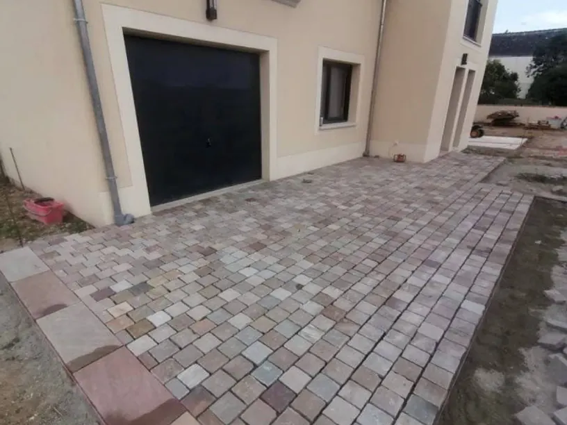 Cour pavée devant l'entrée d'une maison et son garage